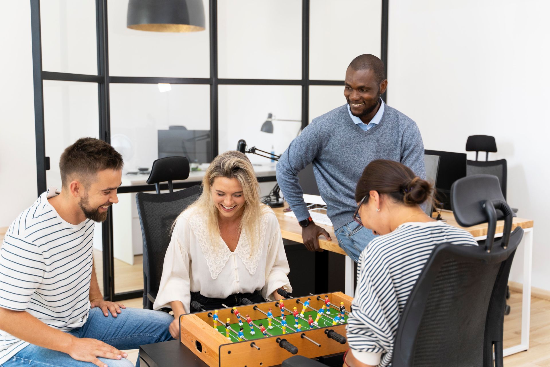 Un groupe de personnes joue au baby-foot dans un bureau.