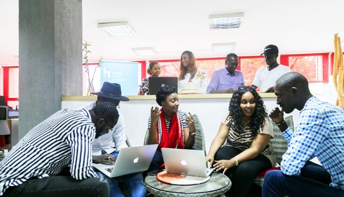 Un groupe de personnes travaillant en collaboration sur des ordinateurs portables autour d'une table dans un bureau moderne et lumineux.