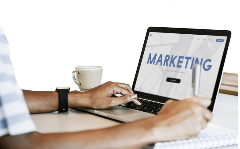 Une personne utilise un ordinateur portable avec le mot marketing sur l'écran.