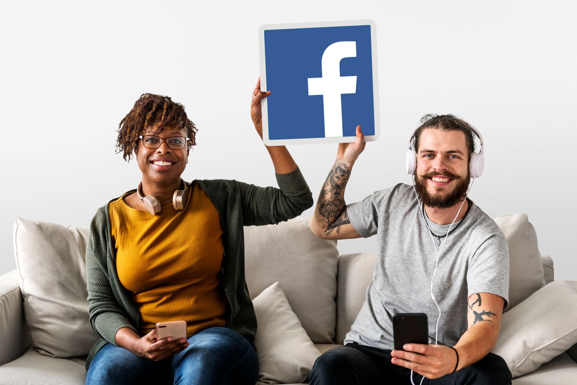 Un homme et une femme sont assis sur un canapé tenant un panneau Facebook.