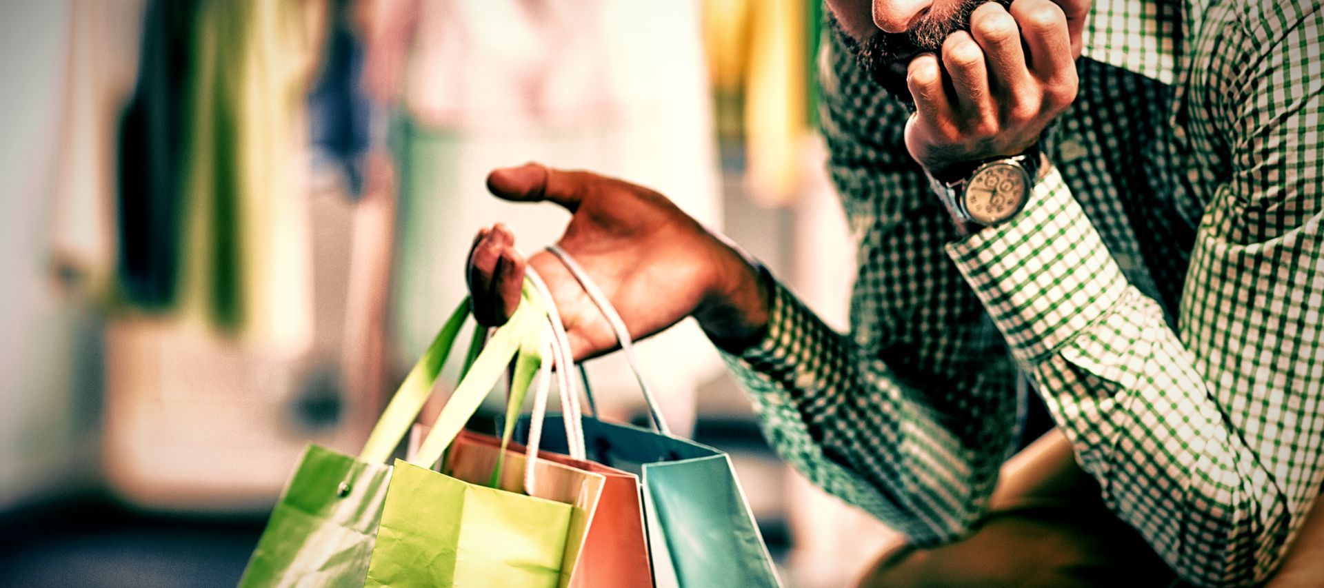 Un homme tient des sacs de courses et parle au téléphone portable.