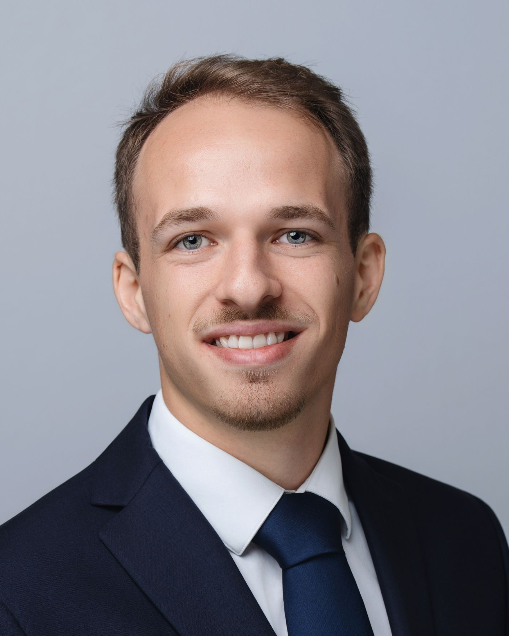Man in suit smiling, looking at the camera.