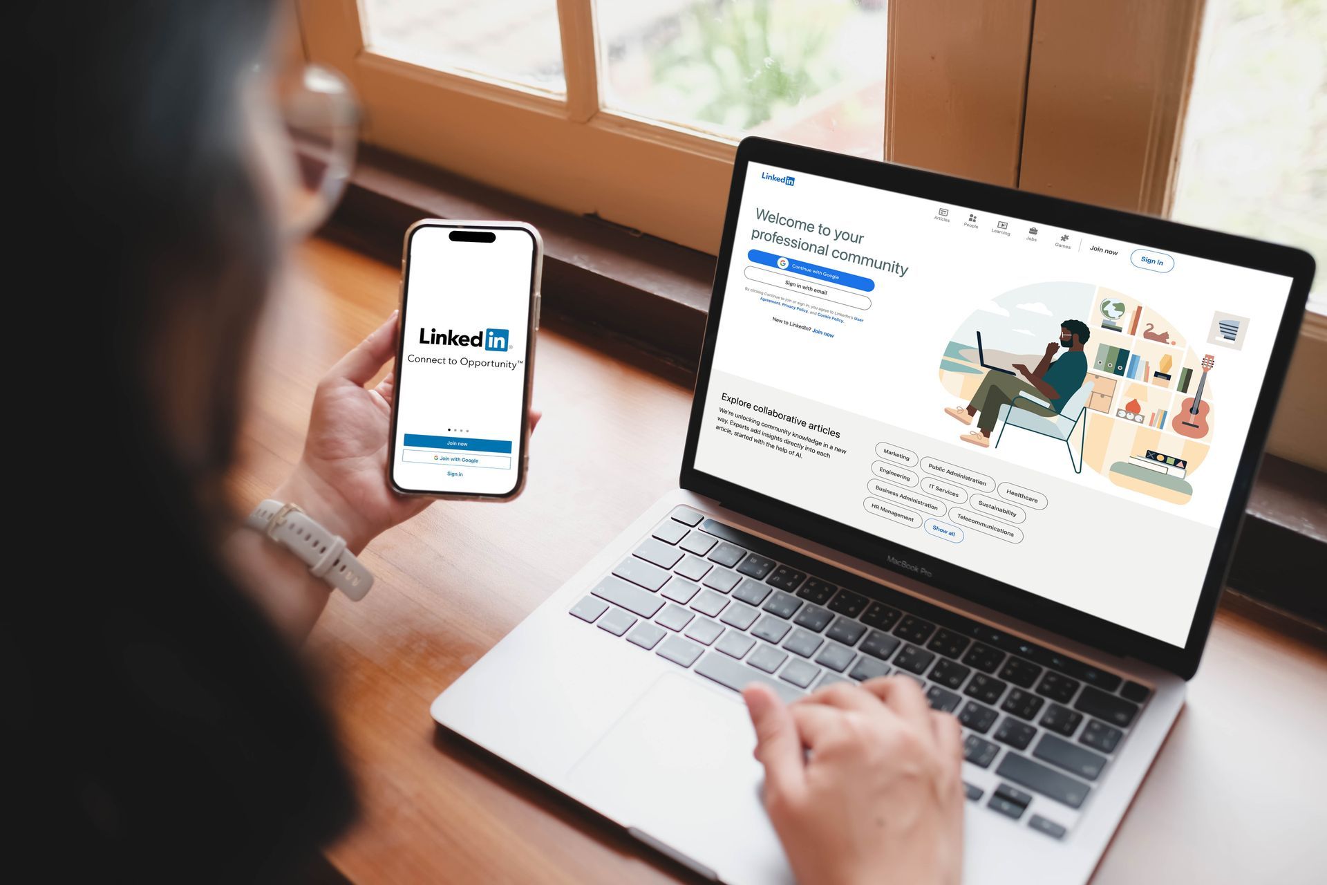 Person using a laptop and phone, both displaying the LinkedIn website.