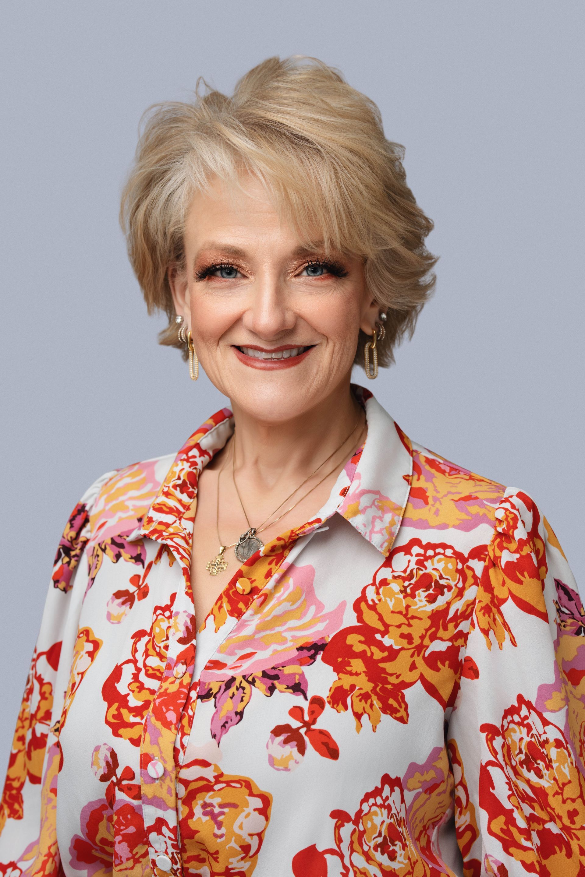Smiling woman in a floral blouse against a light gray background