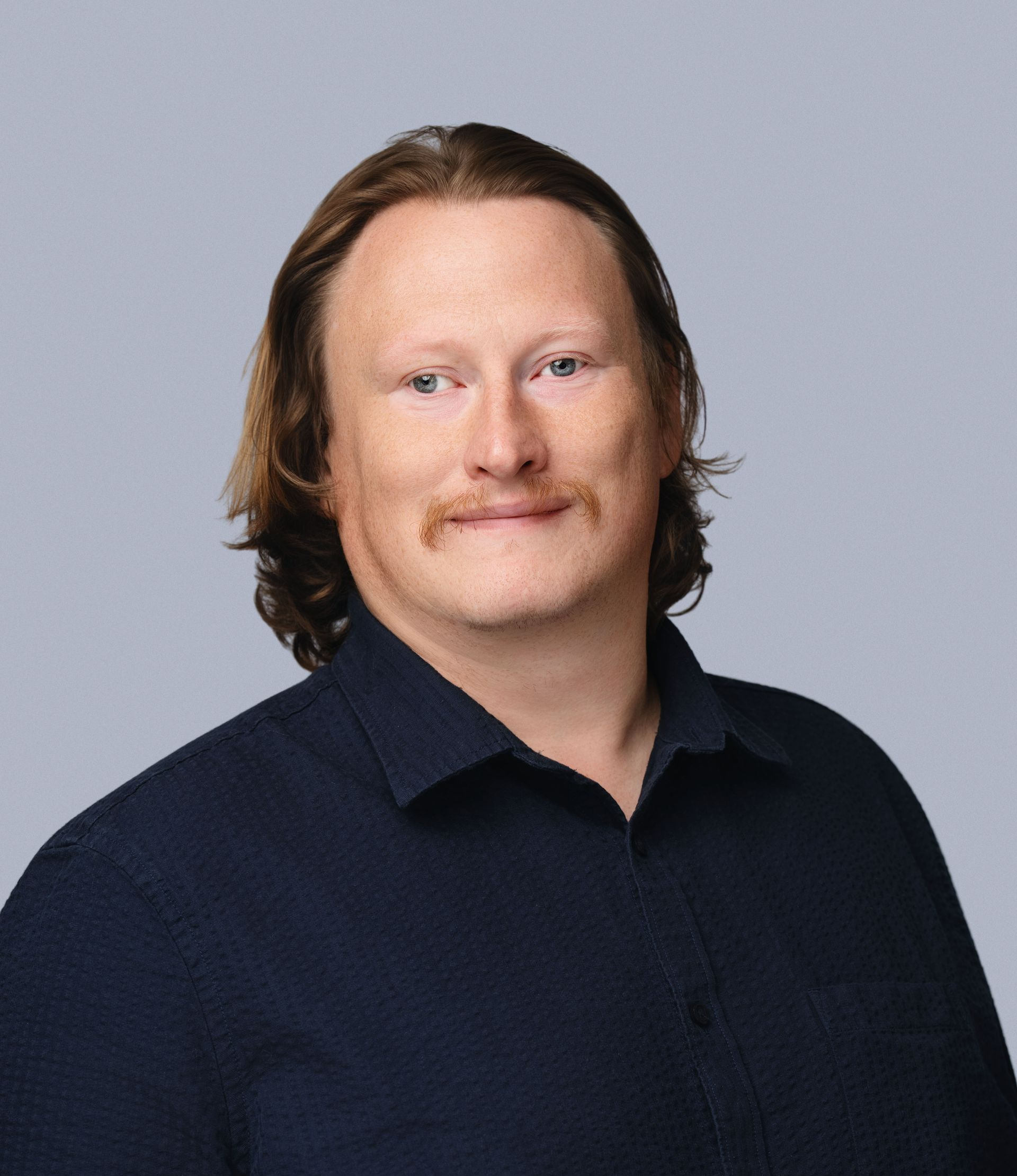 Portrait of a person in a dark navy shirt against a light gray background