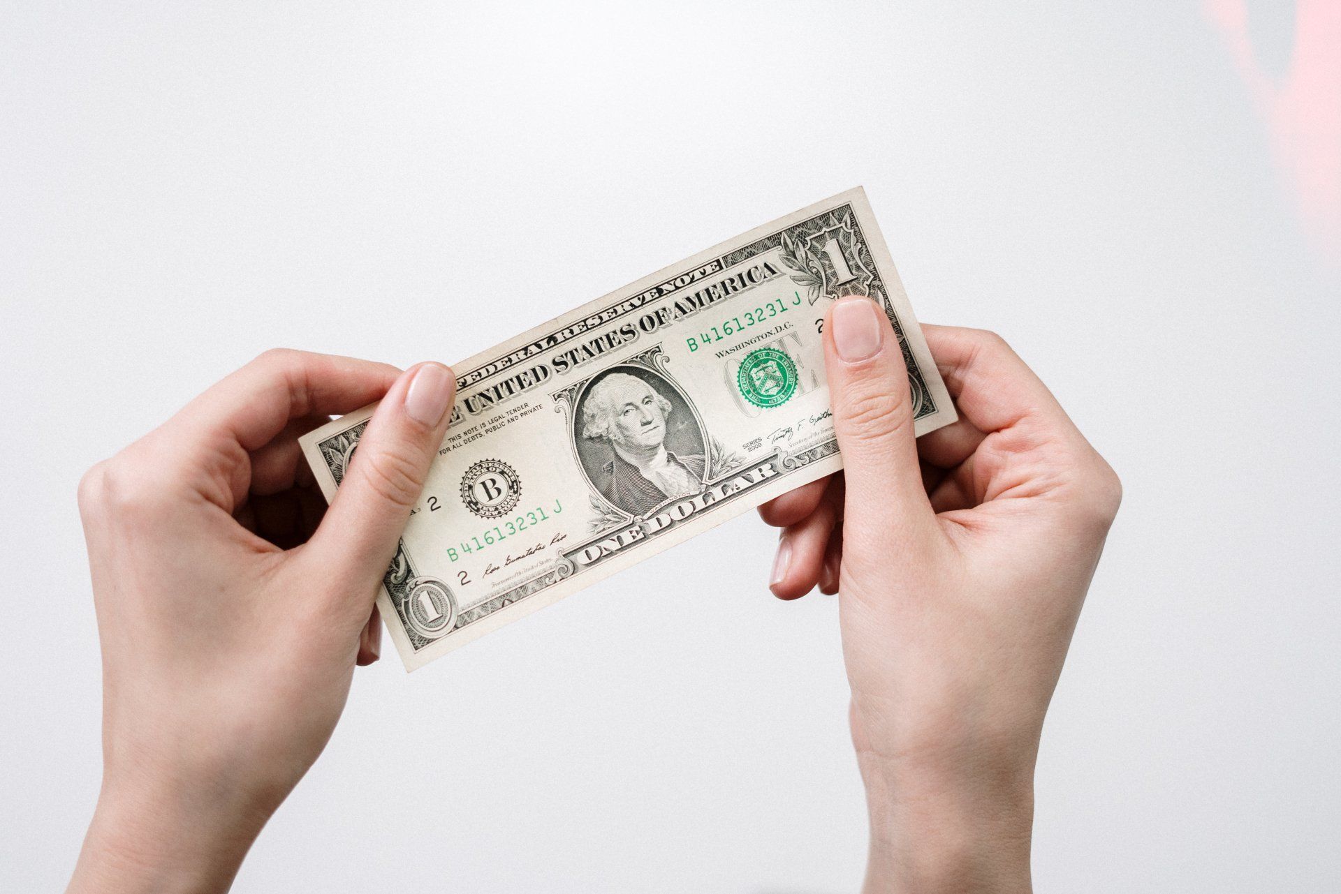 A person is holding a dollar bill in their hands.