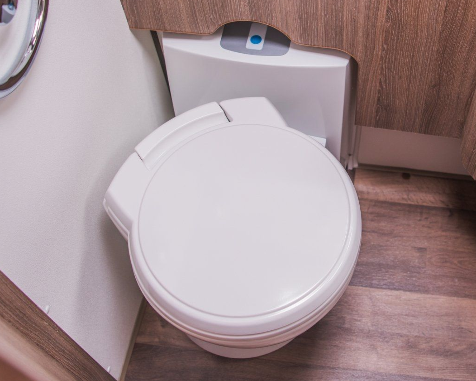 White RV toilet, wood paneling, countertop.