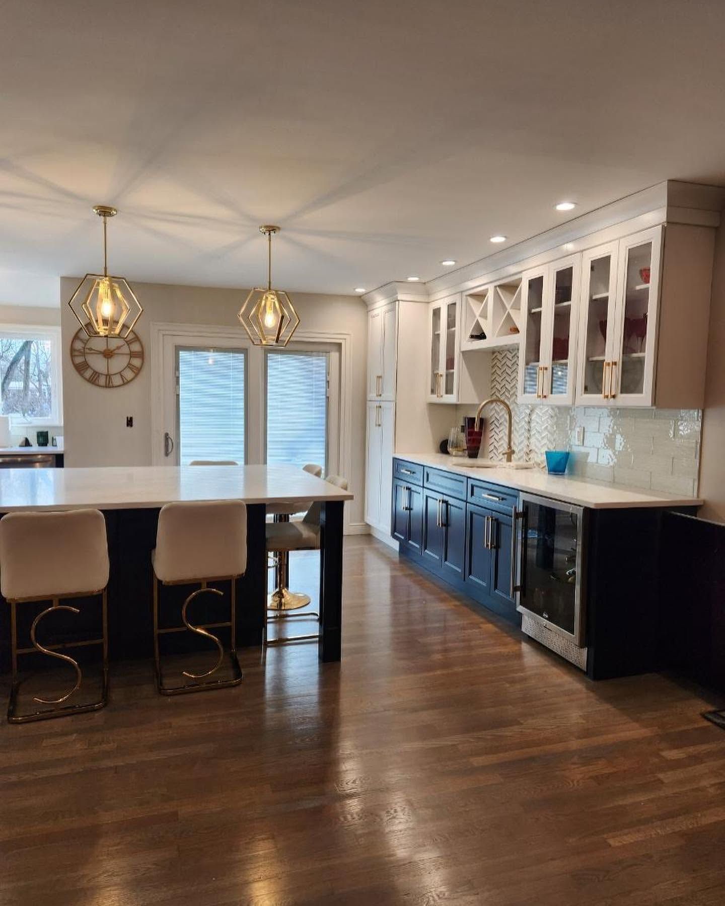 Modern kitchen with island, pendant lights, white cabinets, dark lower cabinets, and hardwood floors.