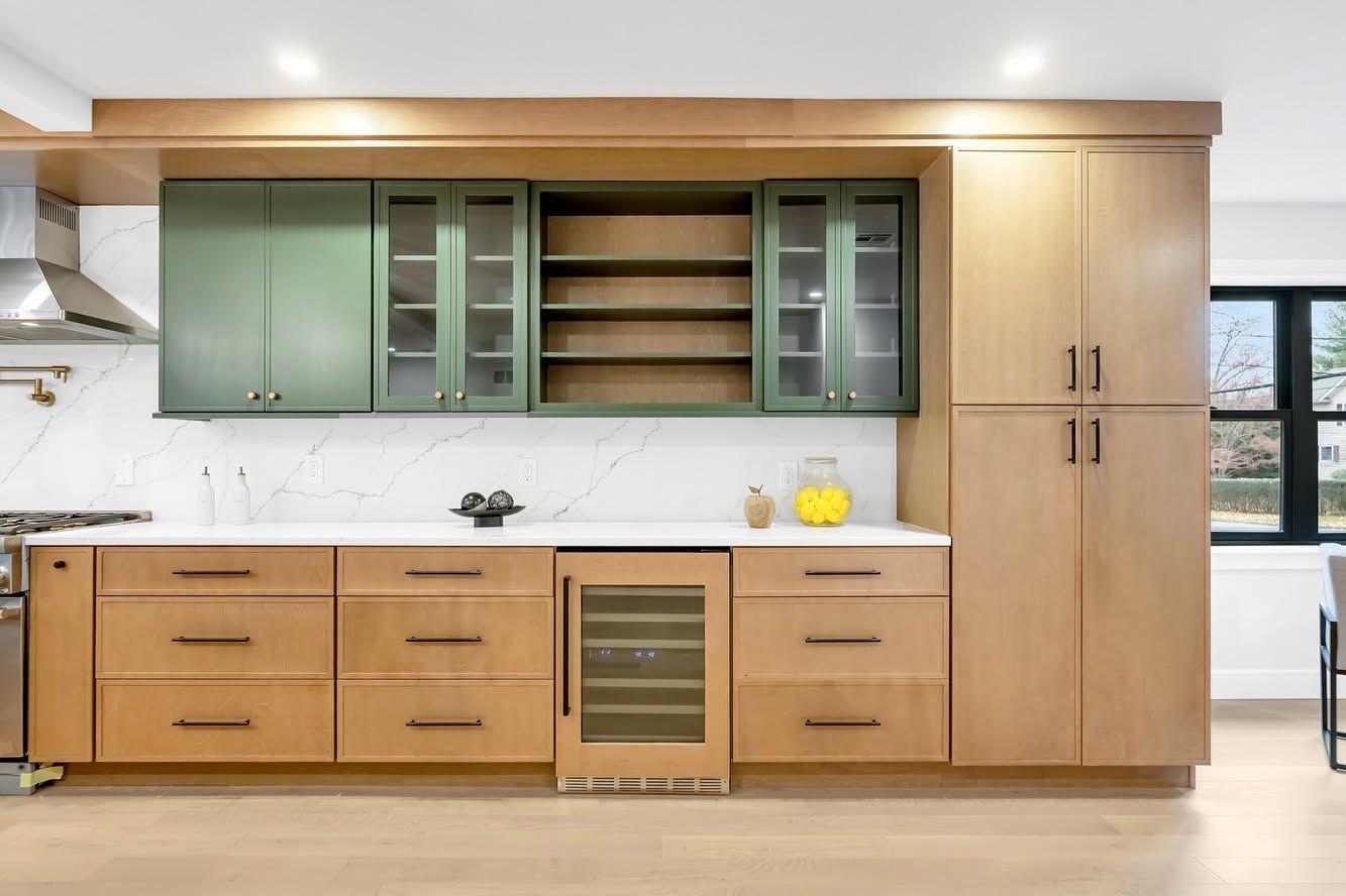 Modern kitchen with light wood cabinets, green upper cabinets, white countertop, and built-in oven