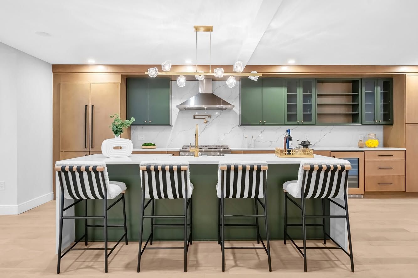 Modern kitchen with large island, bar stools, and wood cabinetry in a bright open space