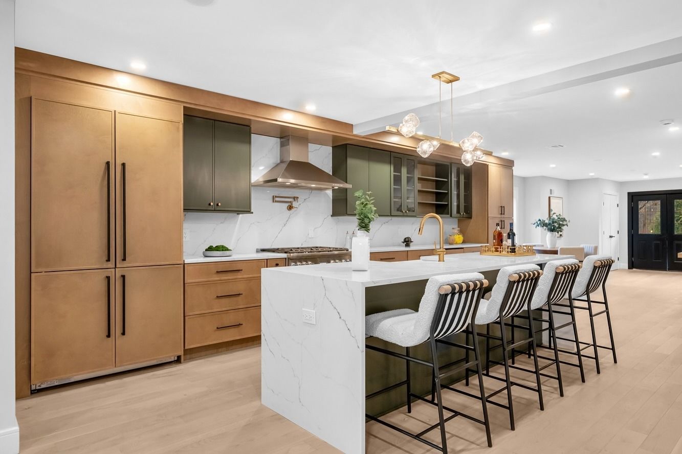 Modern kitchen with wood cabinets, white island, and four barstools under pendant lights