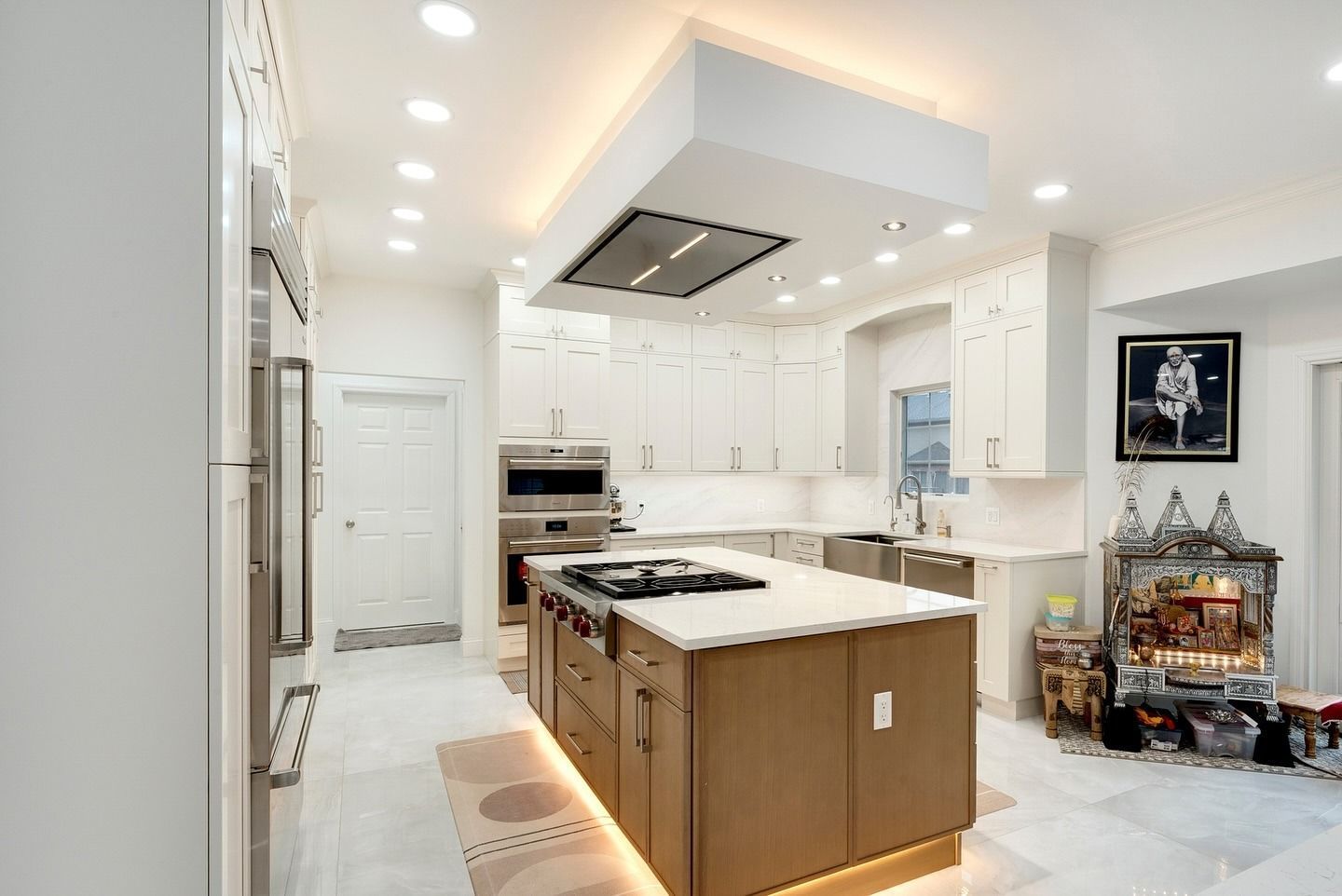 Bright white modern kitchen with island, built-in appliances, and recessed ceiling lights