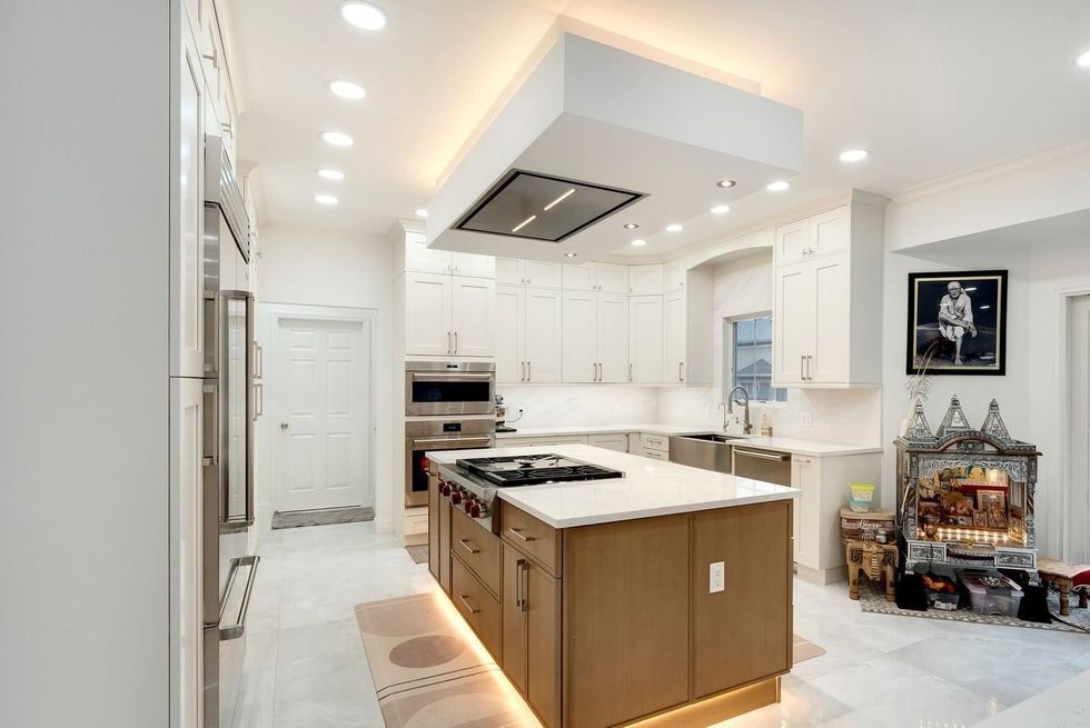 Bright white modern kitchen with island, stainless appliances, and recessed lighting