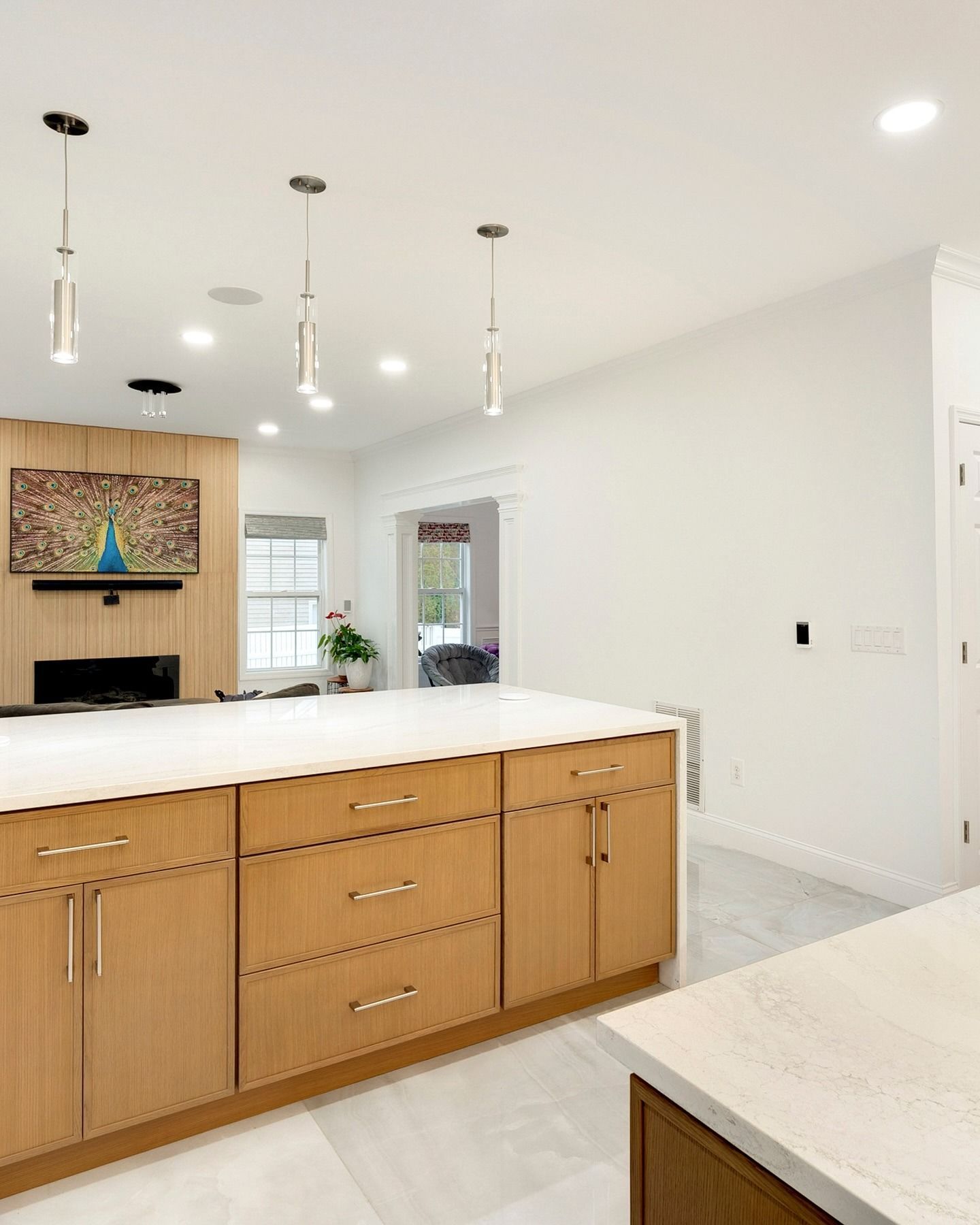 Bright modern kitchen with wood island cabinets, white countertops, and pendant lights
