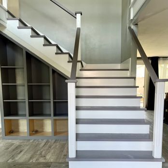 Modern interior staircase with white steps, gray railings, and built-in shelving underneath