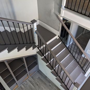 Indoor staircase with gray steps, black railings, and built-in shelving below in a modern home