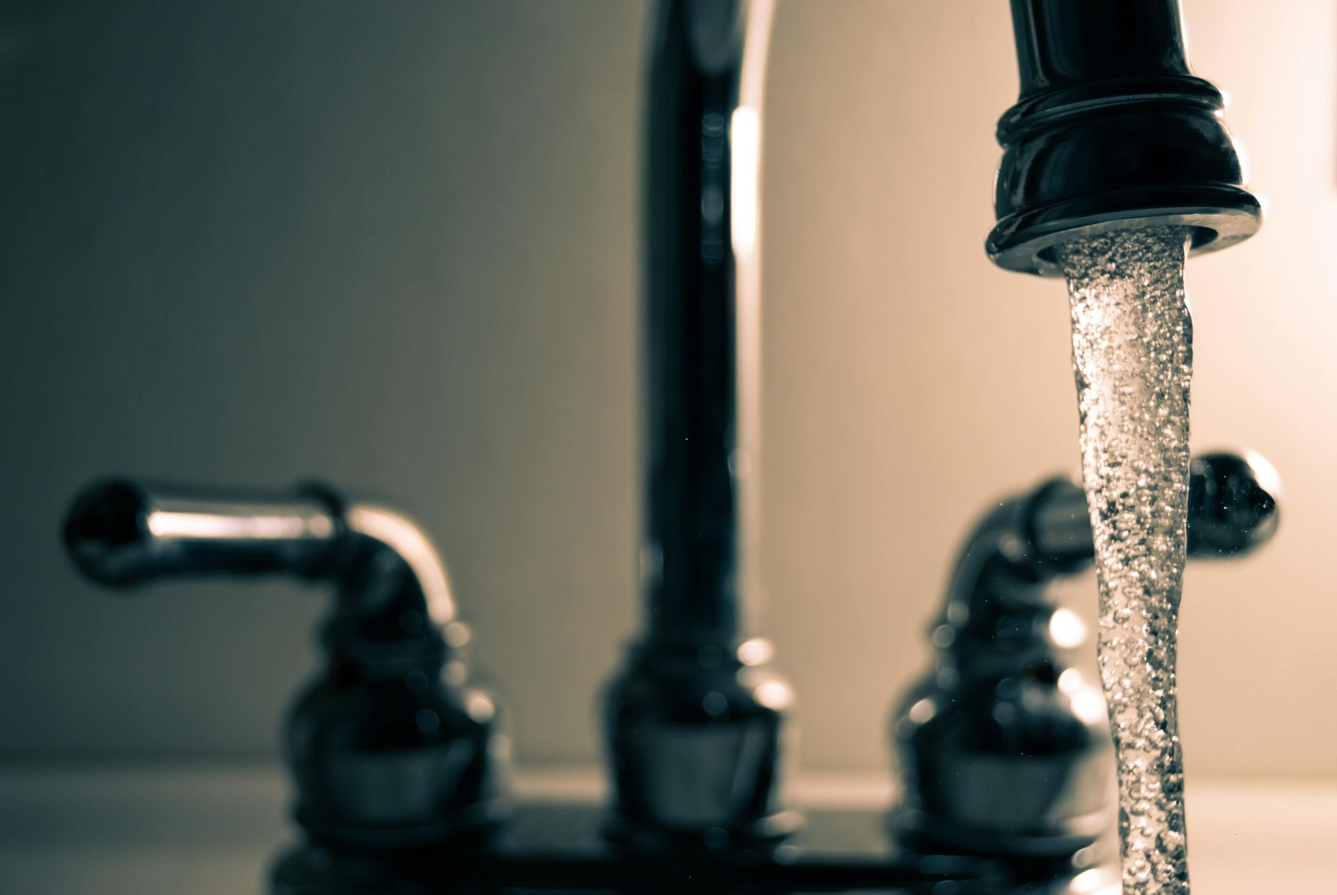 Water flowing from a chrome faucet in a bathroom.