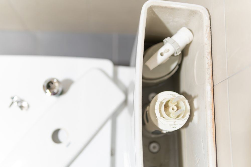 Open toilet tank with exposed plumbing parts.