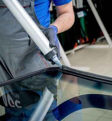 Technician applying adhesive to a car windshield with a caulking gun