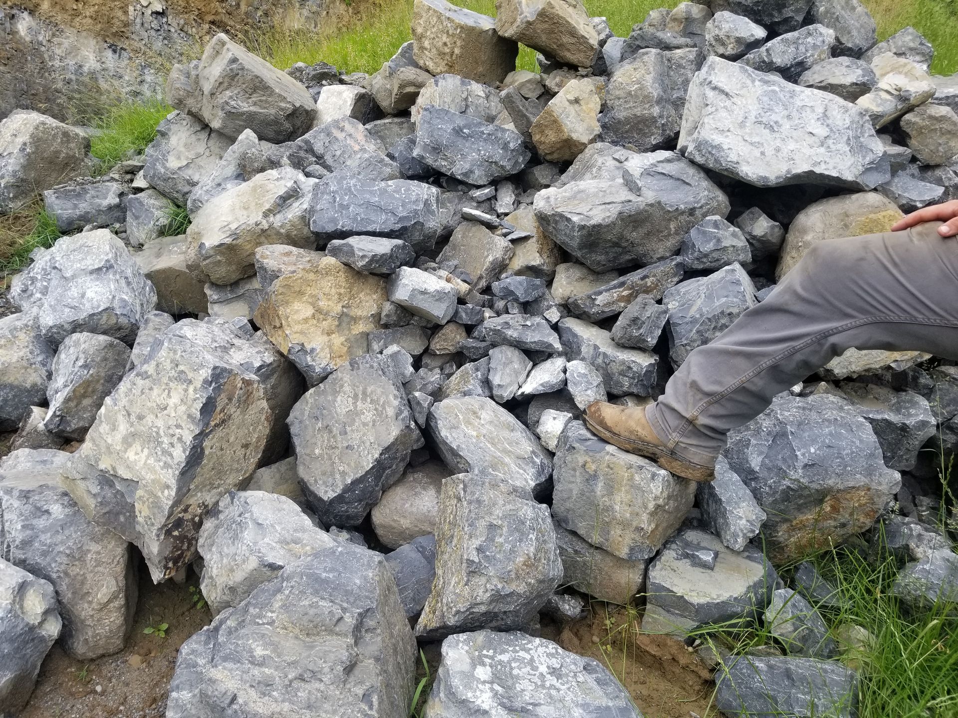 Pile of grey and tan rocks; a person's leg and boot are visible.