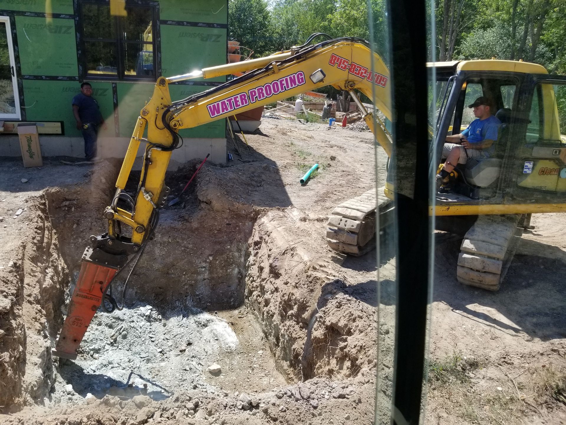 Yellow excavator digging a foundation trench at a construction site. Man operating the machinery.