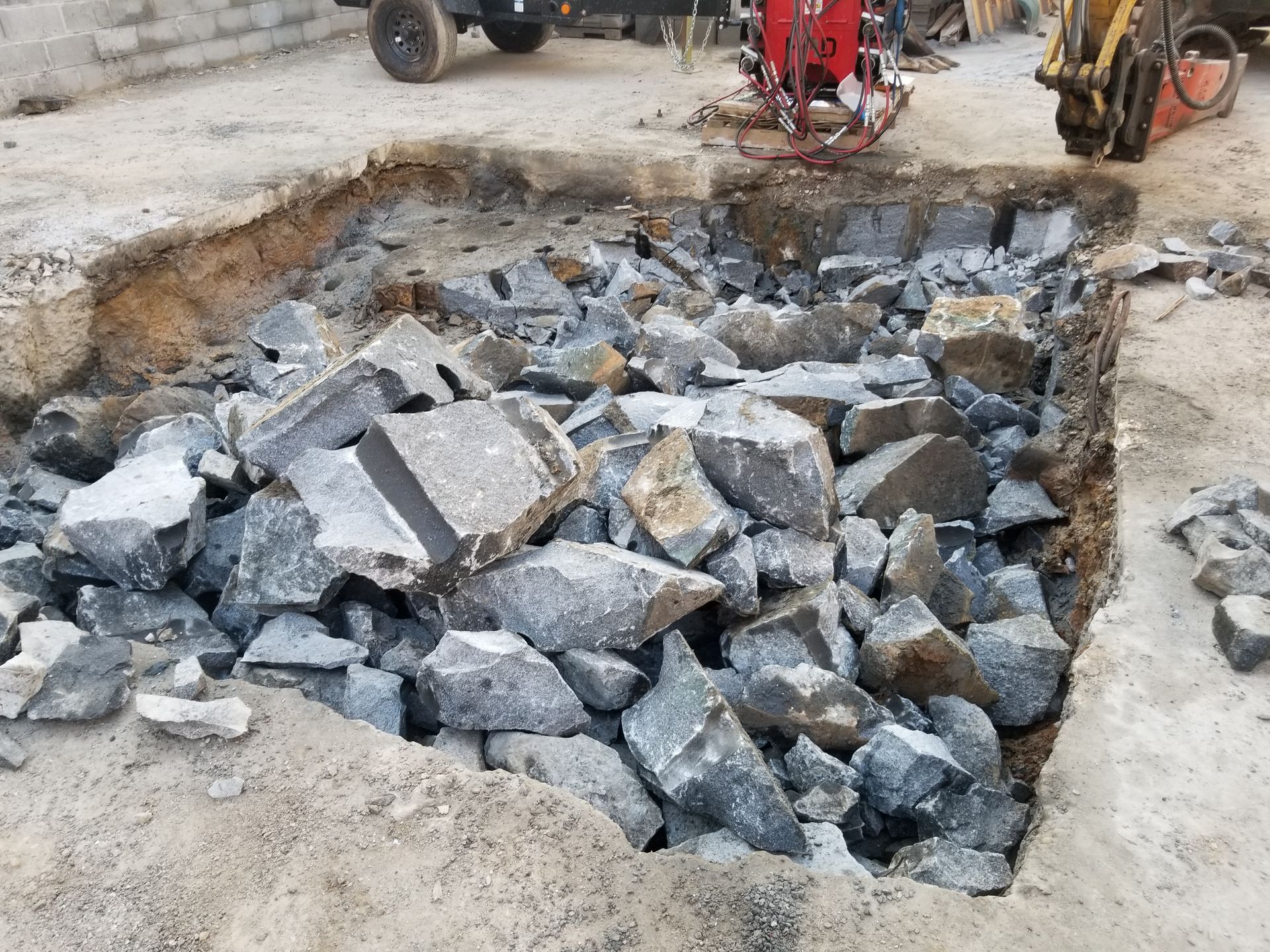 Pile of broken gray rocks in a excavated square, construction site.