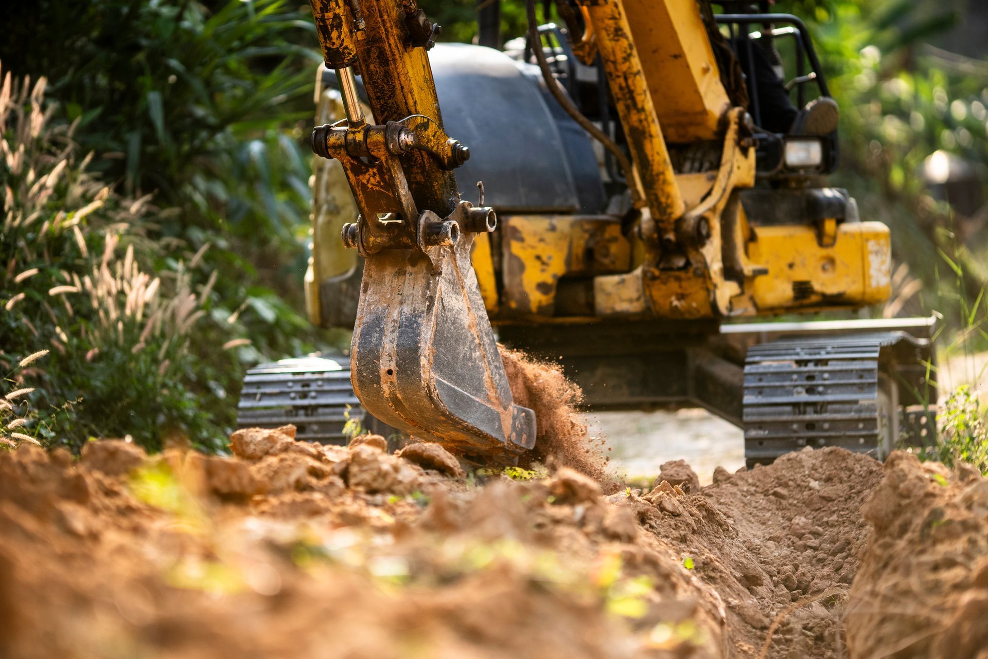 Yellow excavator digging soil during land excavation work at construction site. Yellow excavator digging soil during land excavation work at construction site.