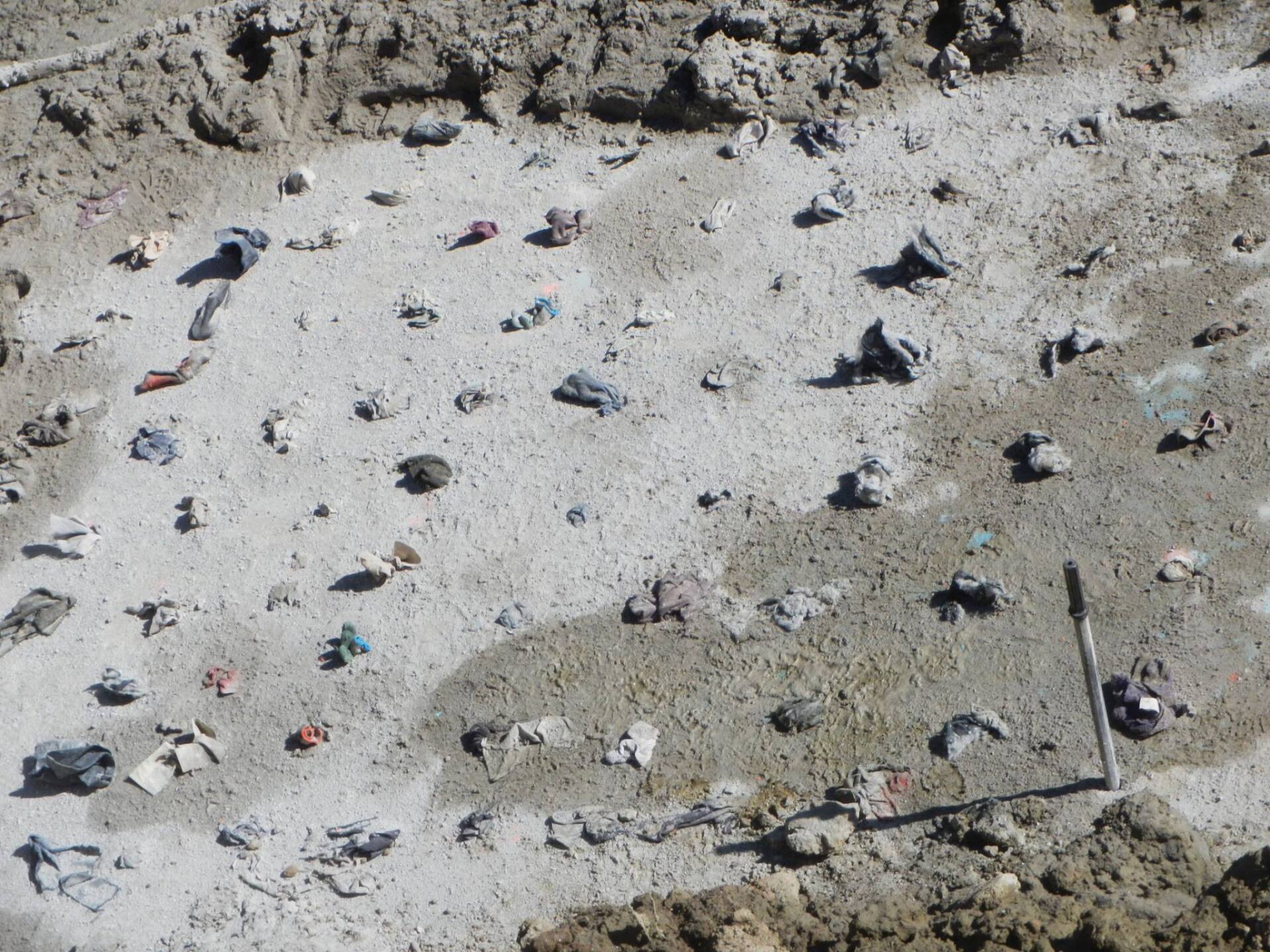 Ground covered in debris, including rocks and colorful fragments, likely a construction site.