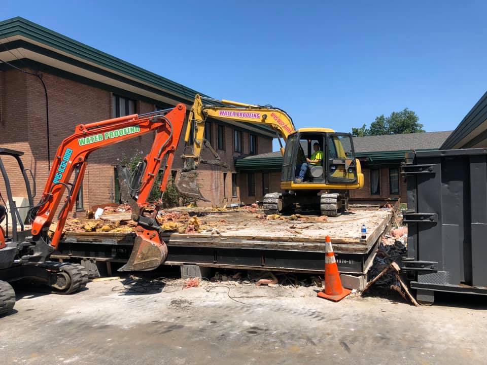 Construction site with excavator and bulldozer demolishing a building's structure.