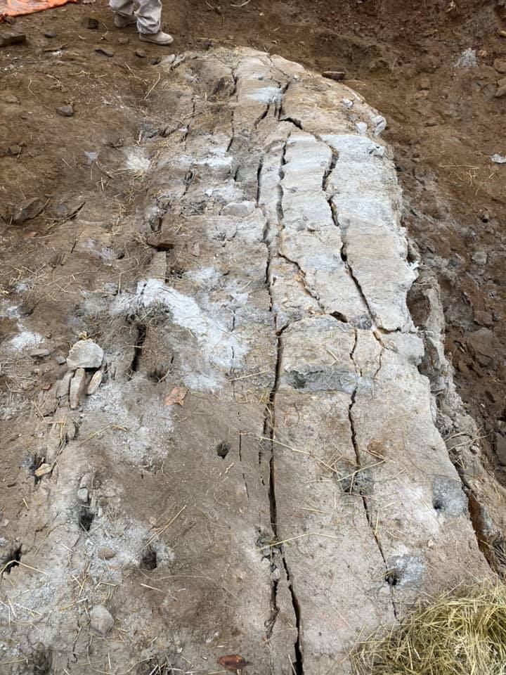 A large, cracked concrete block in a dirt excavation. White patches and holes are visible on the surface.