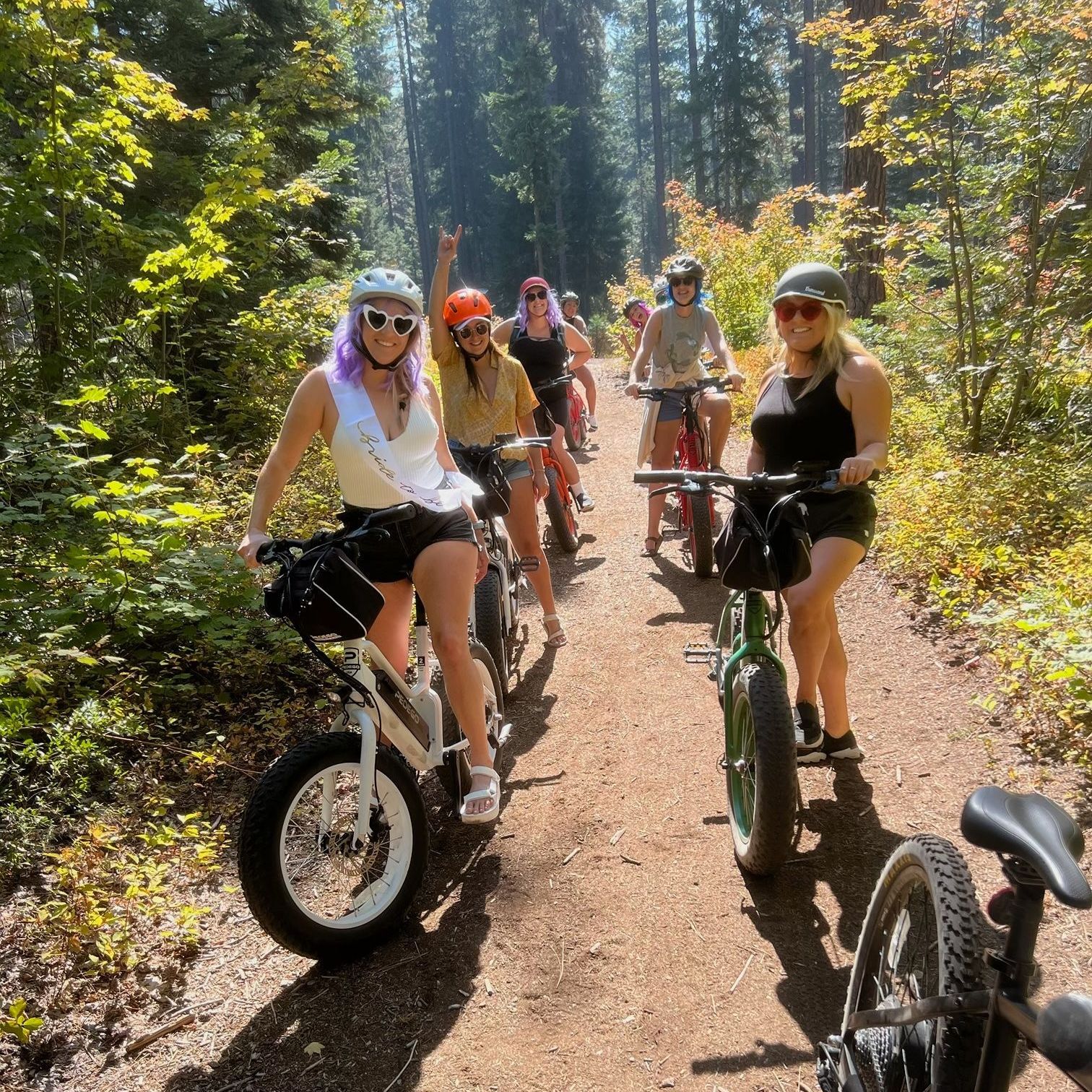 A group of people are riding bikes on a dirt path in the woods.