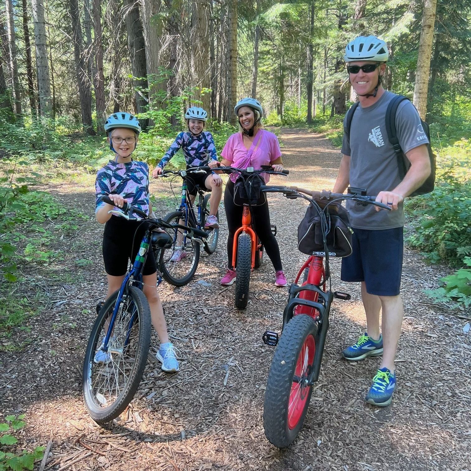A group of people are riding bikes in the woods.