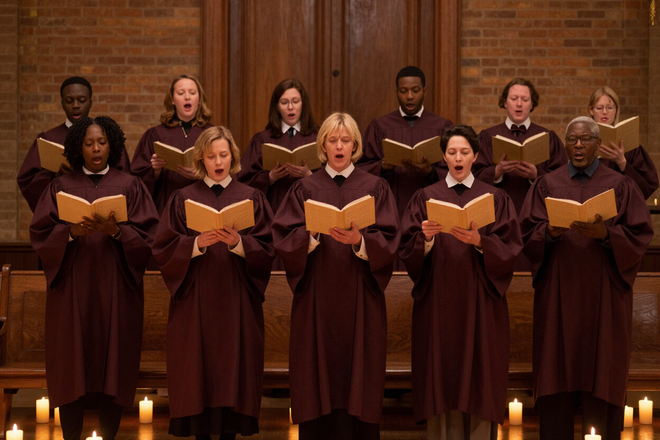 Church choir singing with hymnals open in warm candlelight