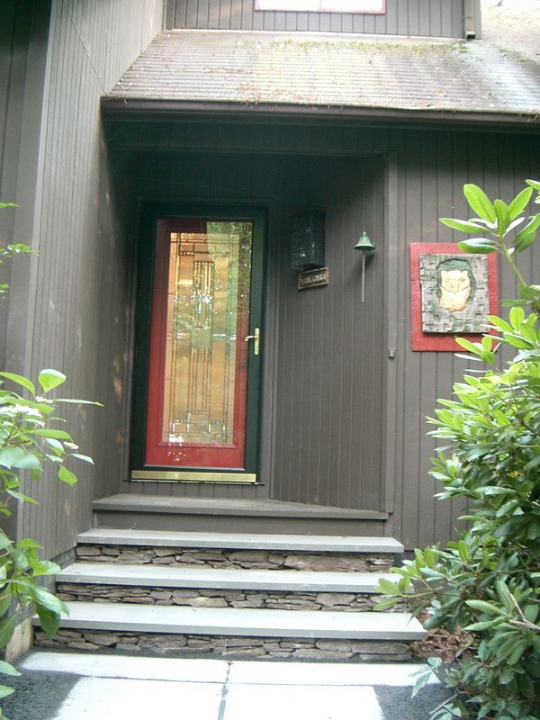 Brown house entrance with red door, stone steps.