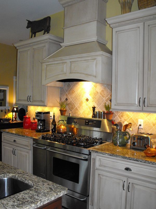 Kitchen with stainless steel range, light cabinets, granite countertops, and decorative cow statue atop the hood.
