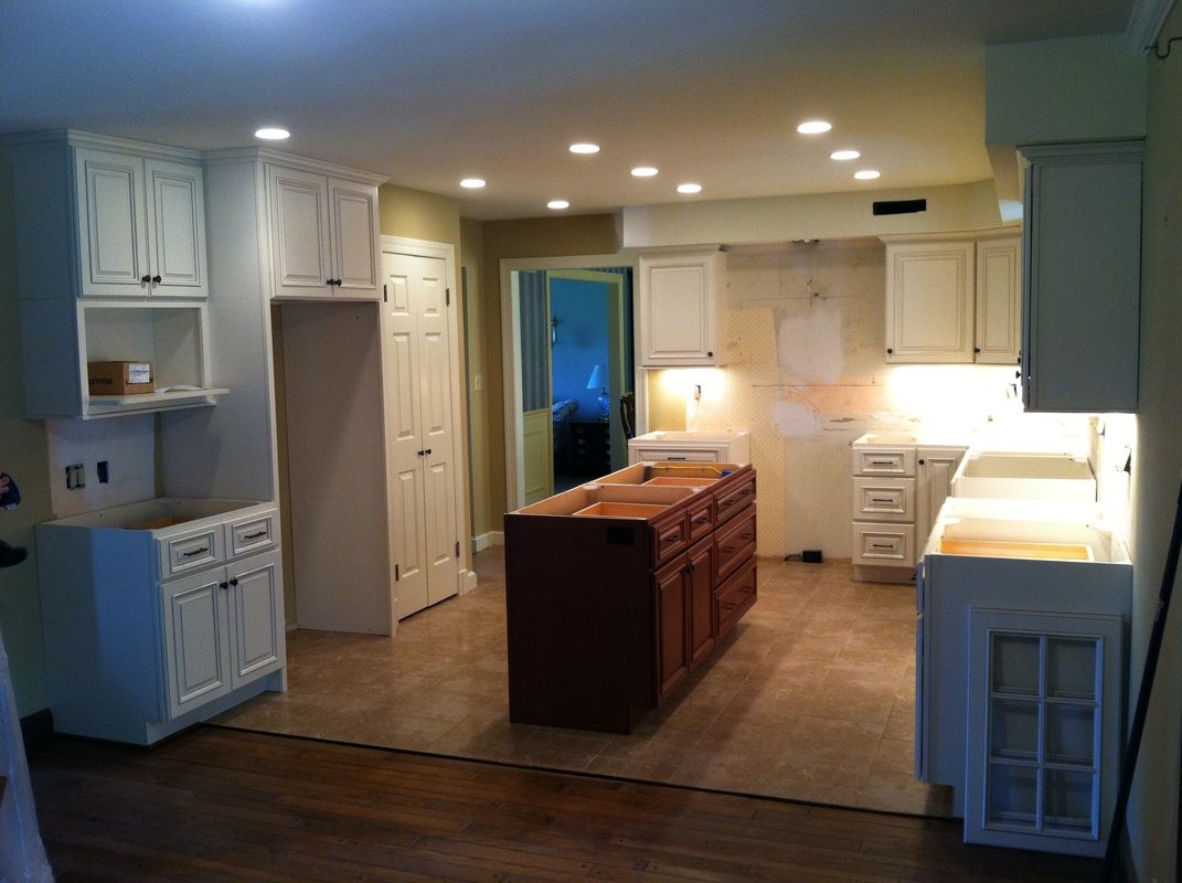 Kitchen renovation with white cabinets, wood island, and recessed lighting.
