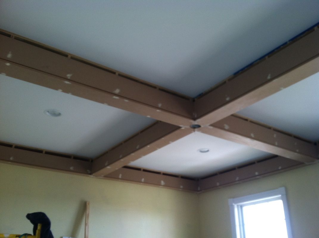Beamed ceiling construction, light-colored beams intersecting on a white ceiling.  Drywall and lighting visible.