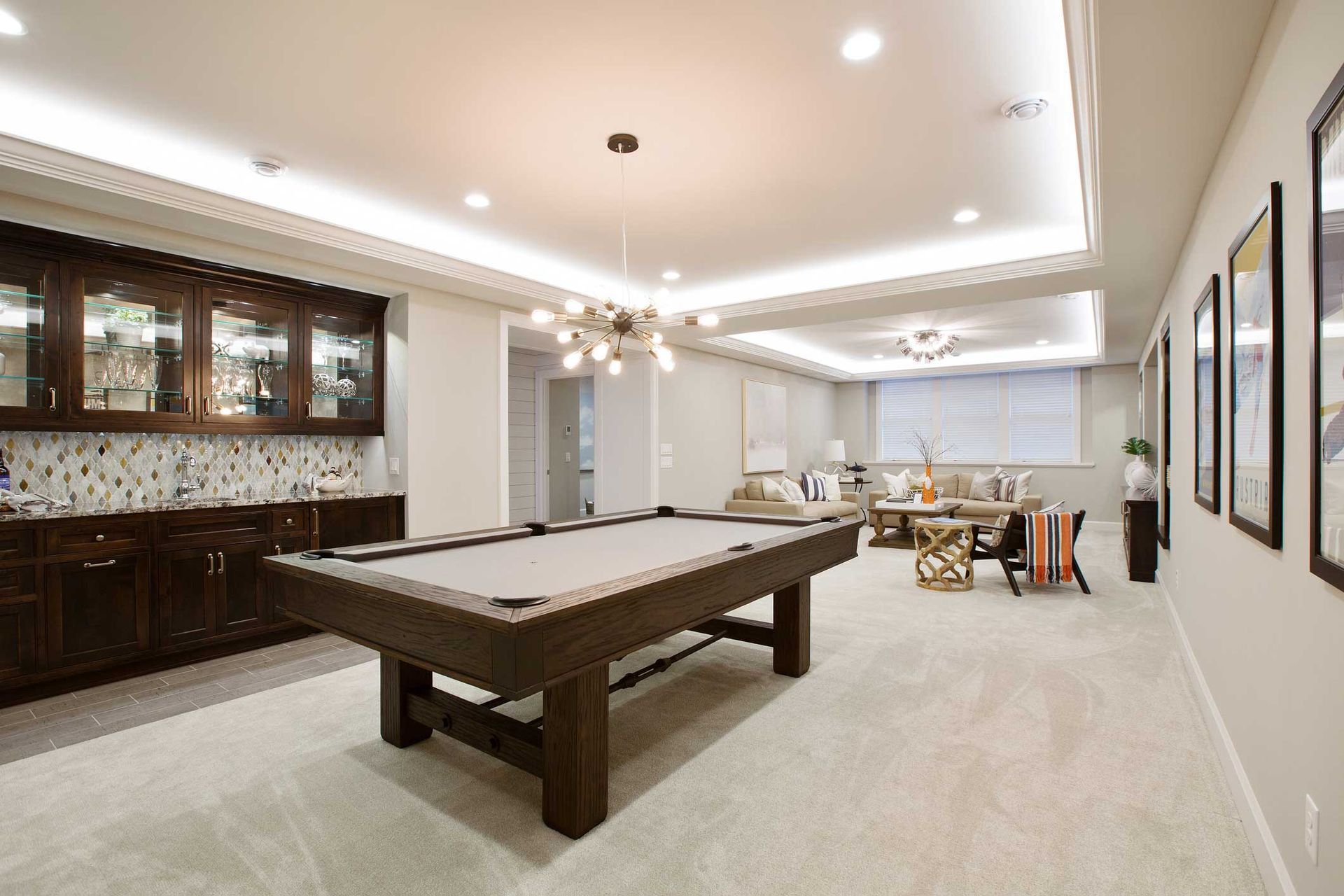 Spacious basement with pool table, bar, and seating area. Neutral colors, recessed lighting, and modern decor.