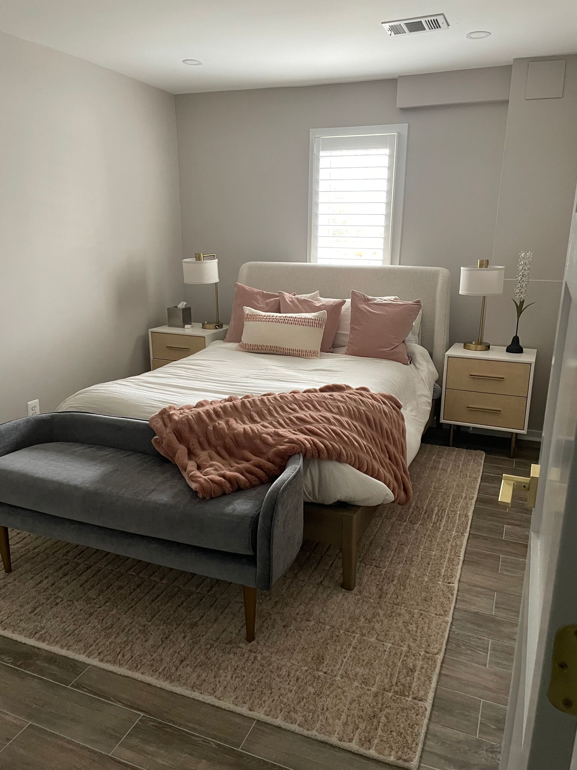 Bedroom with bed, nightstands, rug, bench, and decorative pillows in neutral tones.