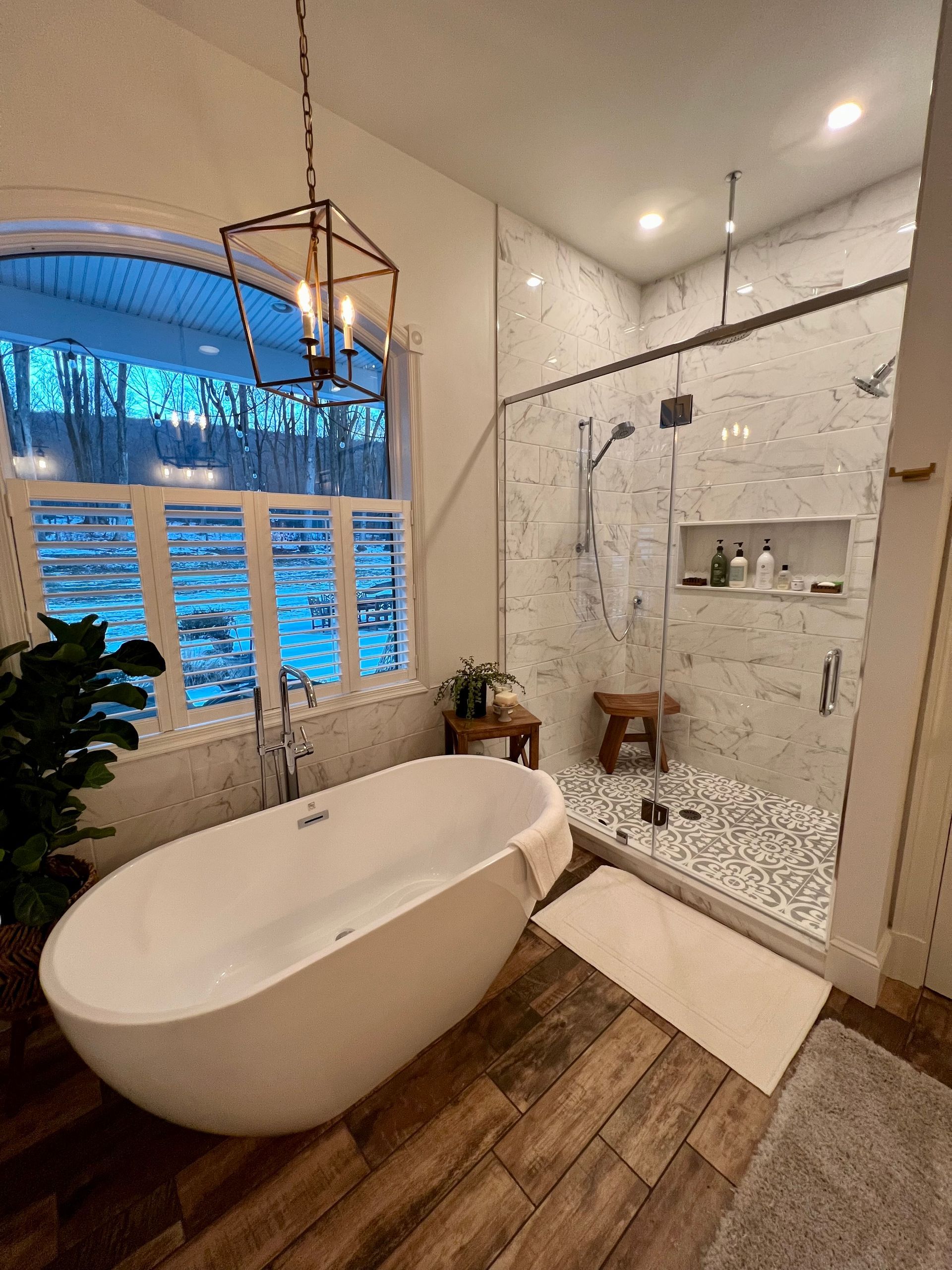 Luxurious bathroom with soaking tub, glass shower, and wood-look flooring.