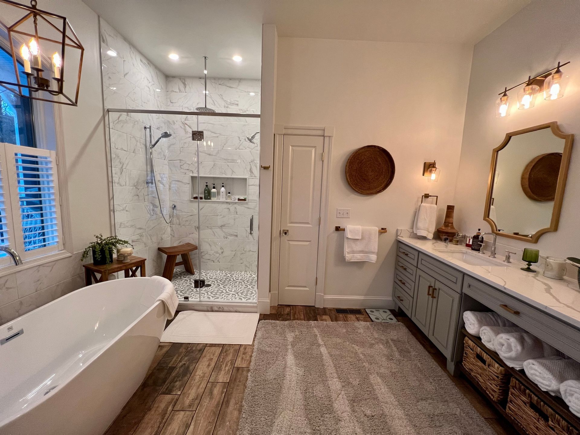 Spacious bathroom with a white tub, walk-in shower, double vanity, and wood-look flooring.