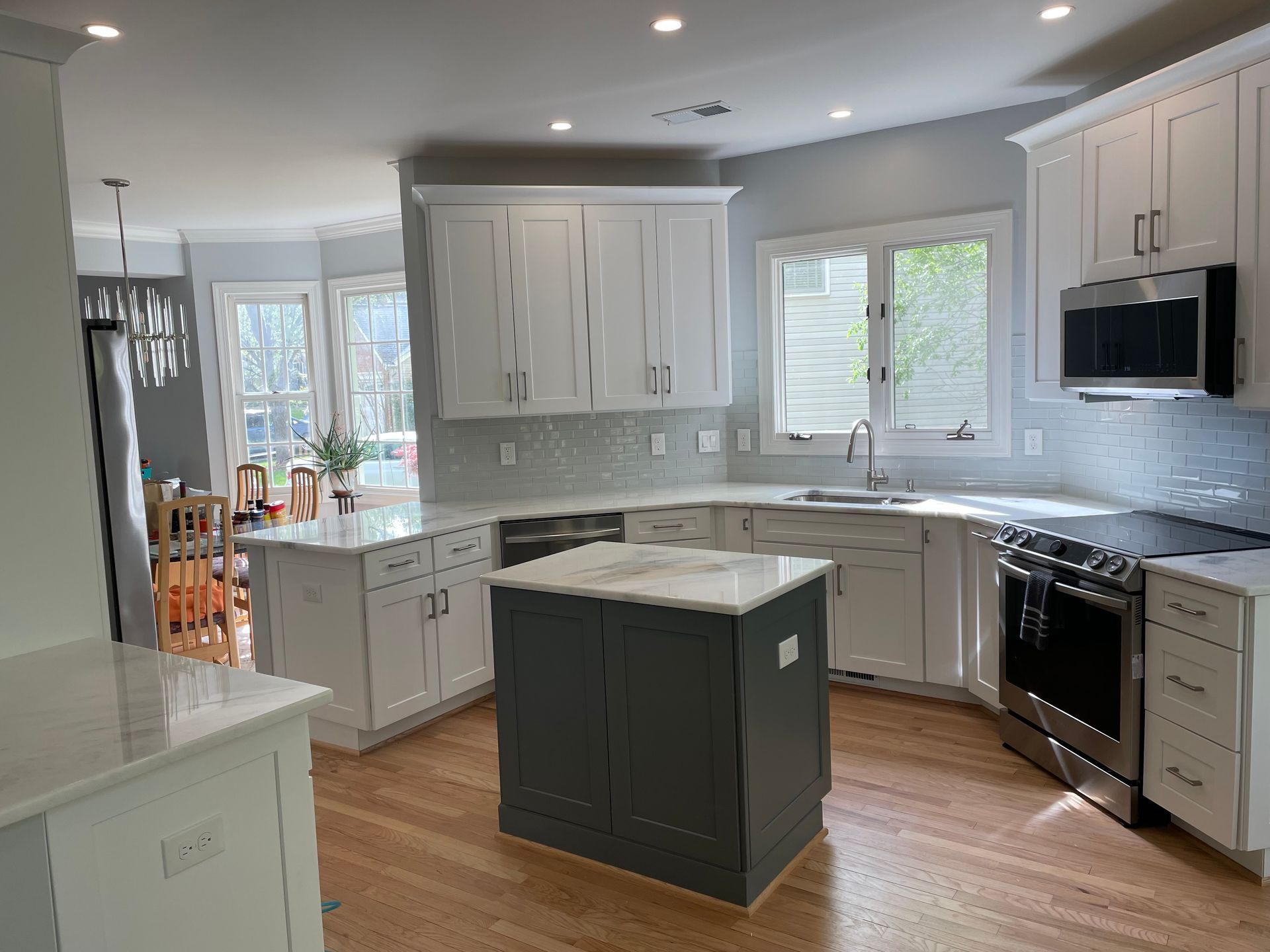 Modern kitchen with white cabinets, gray island, and stainless steel appliances.