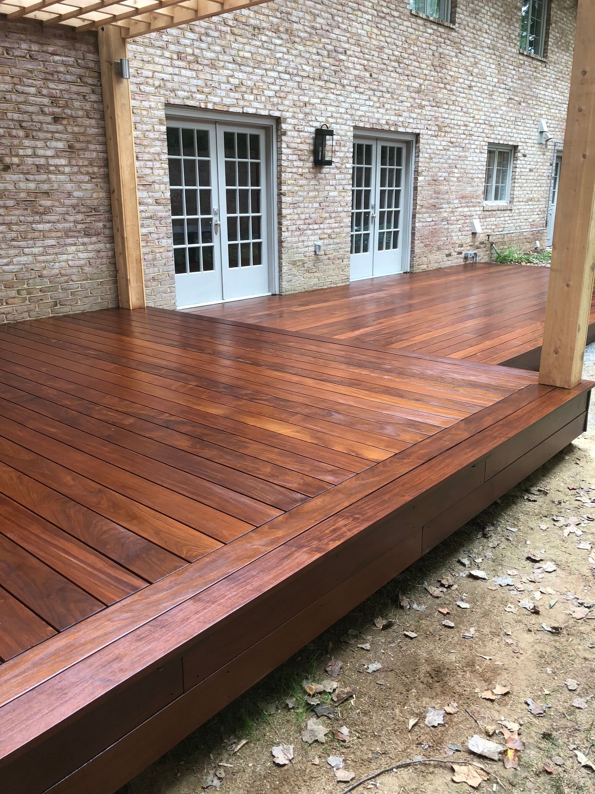 Wooden deck extending from a brick building with white French doors.