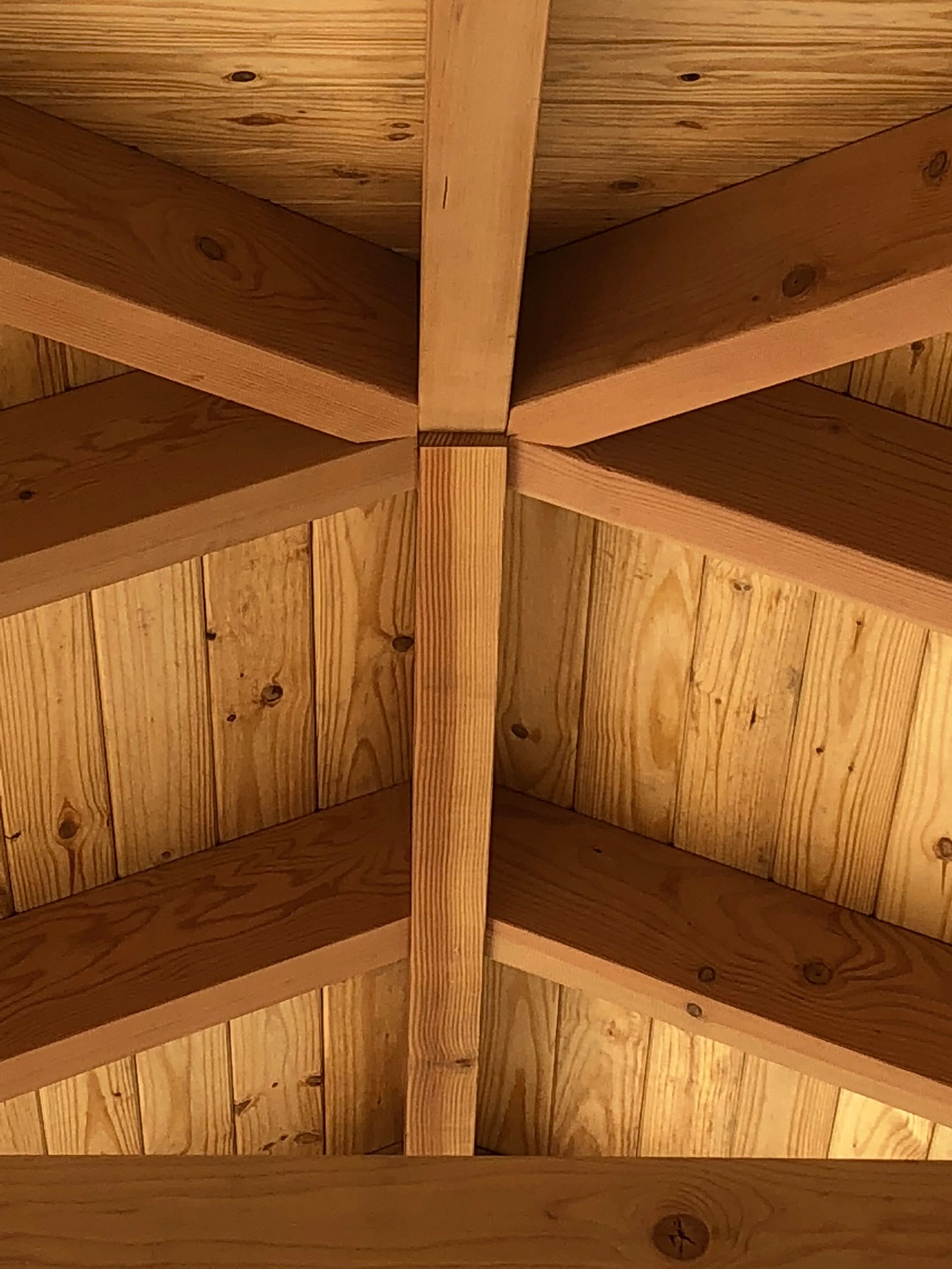 Wooden roof structure with beams converging on a central support post.