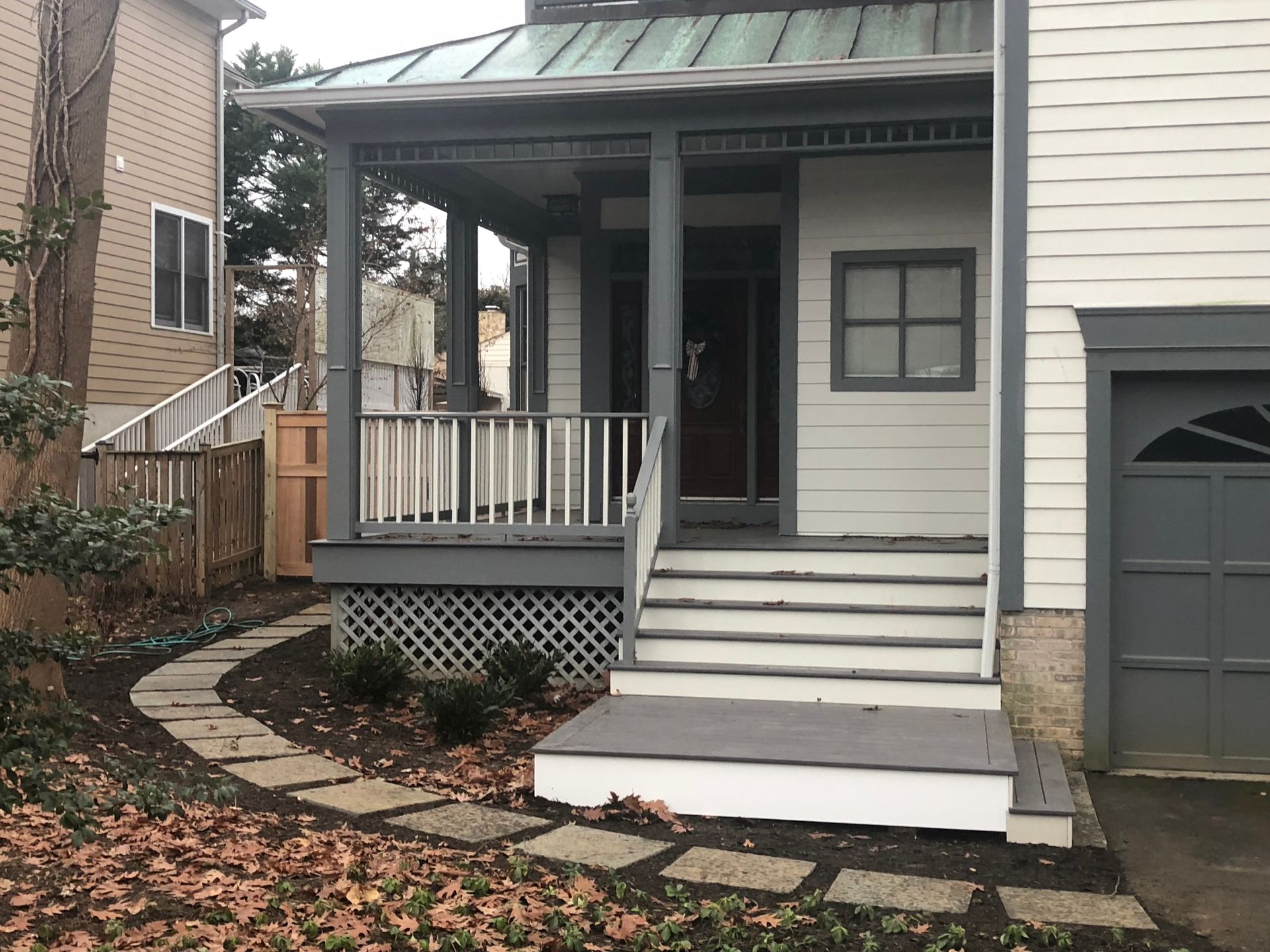 Gray house with a front porch, stone walkway, and a garage.