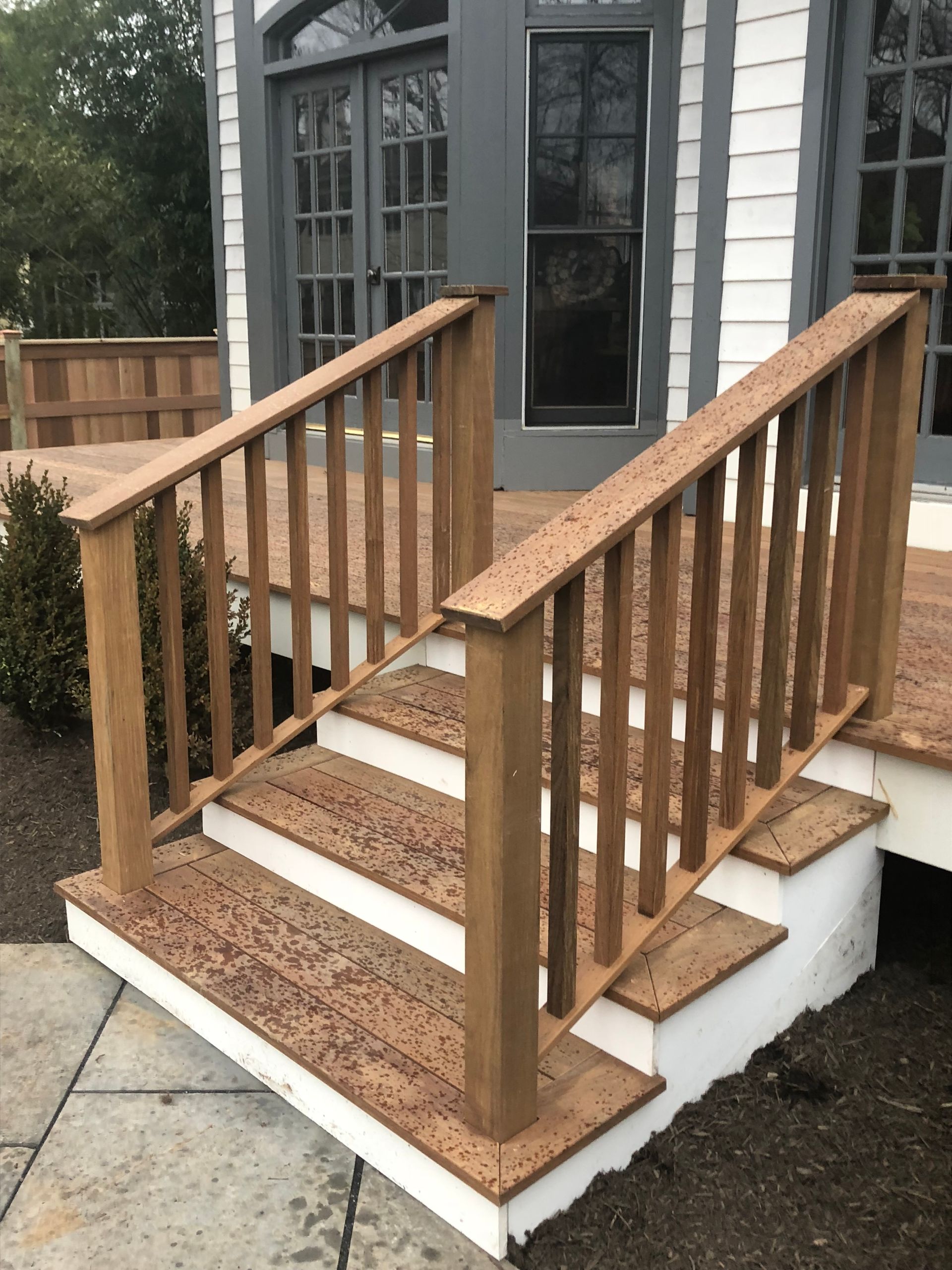 Wooden staircase with handrails leading to a deck outside a building.