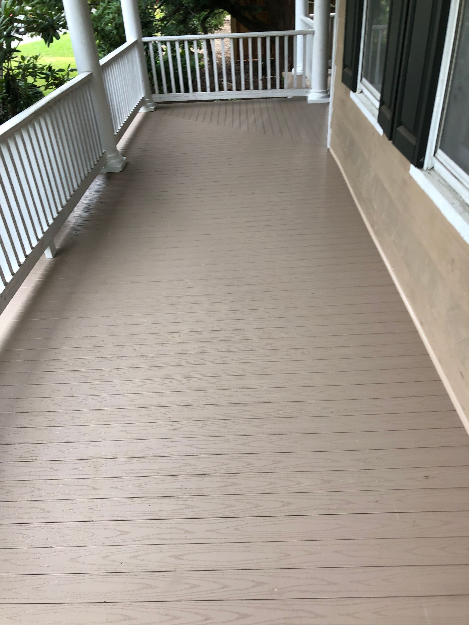 Tan painted porch with white railing, viewed from above.