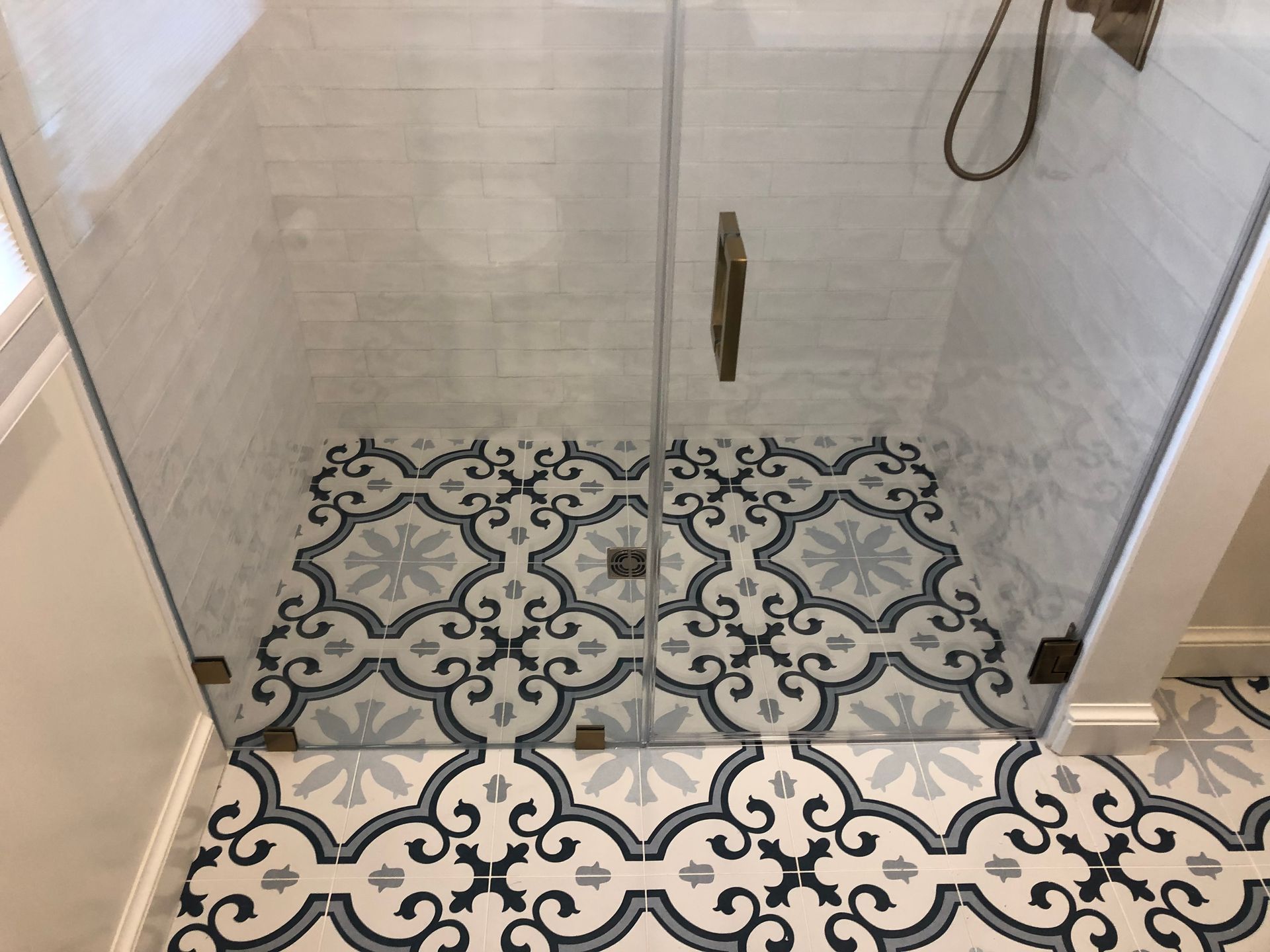 Shower with glass doors and decorative blue and white tile floor.