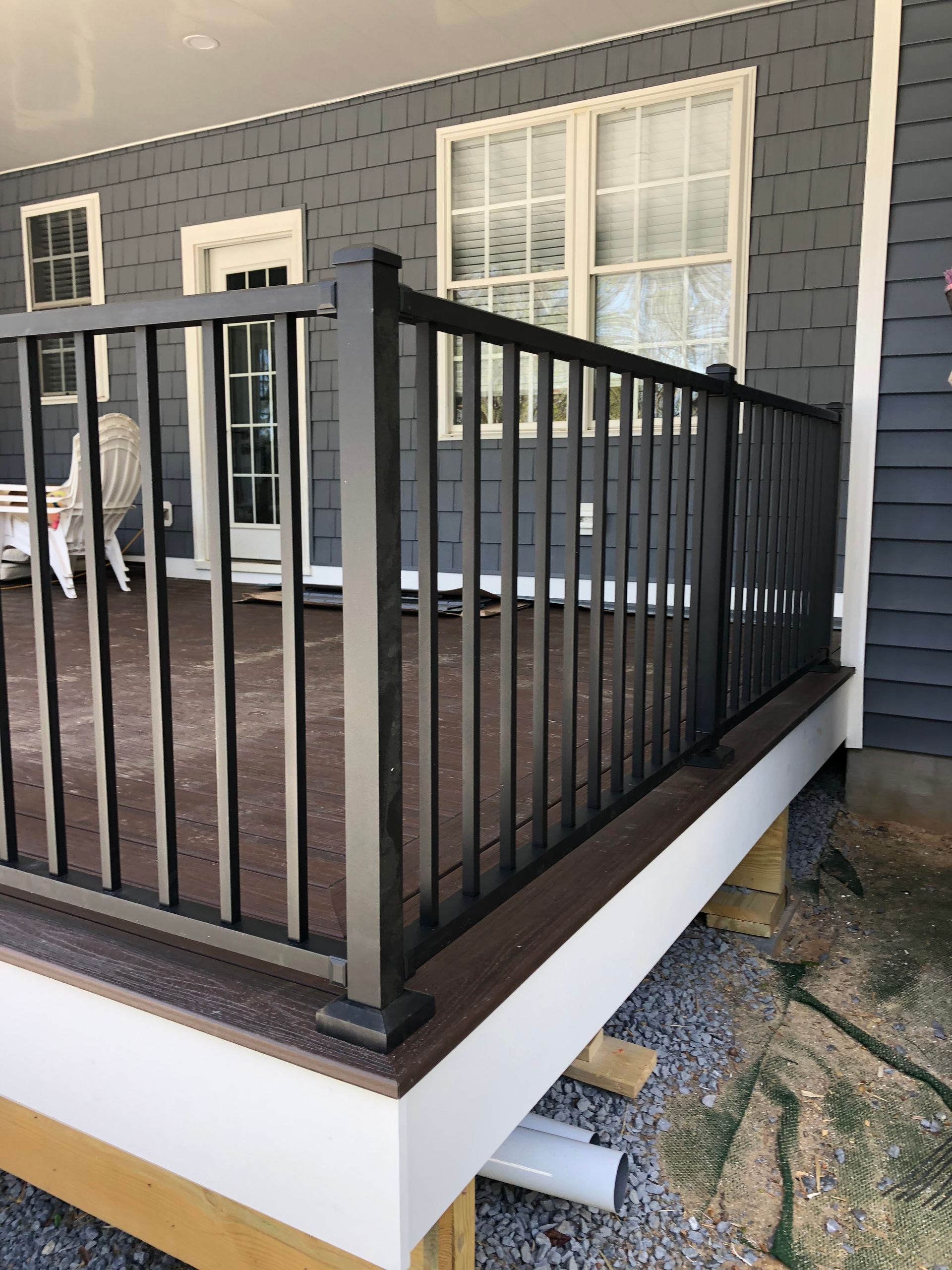 Black deck railing on a deck with gray siding.