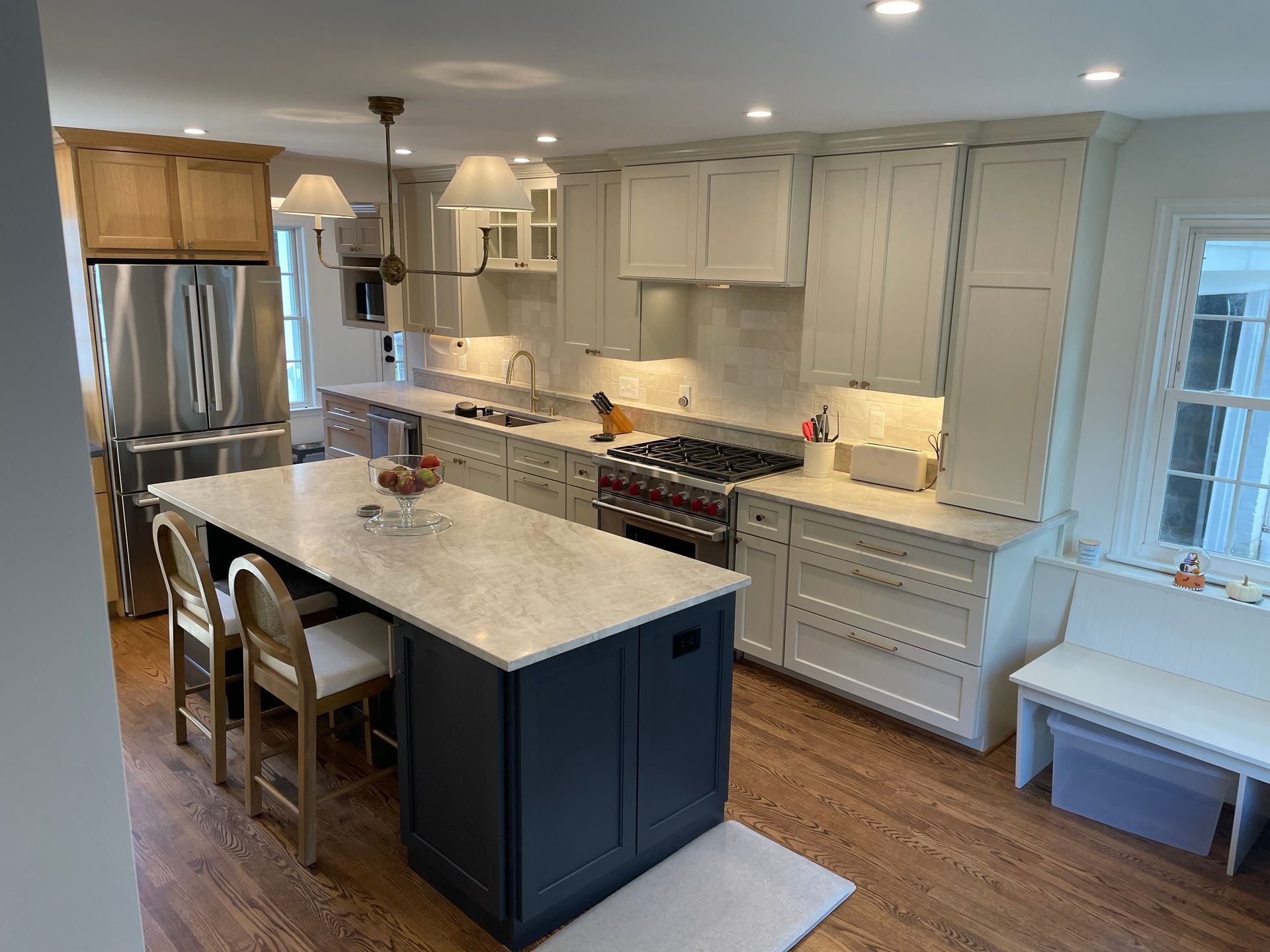 Kitchen with white cabinets, blue island, stainless steel appliances, and wood floors.
